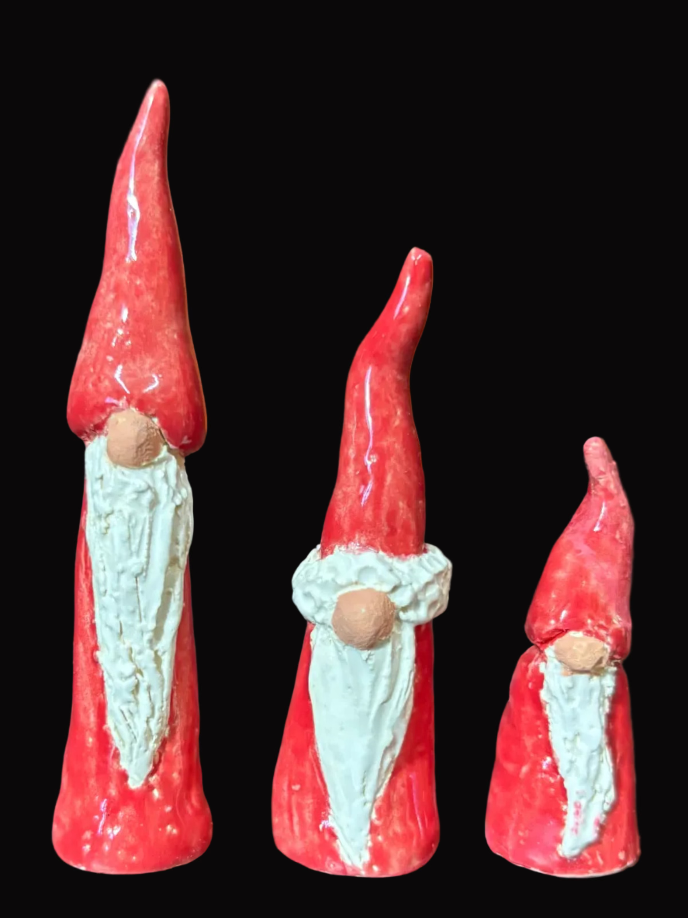 Three red gnome figurines on a dark surface with a blurred background